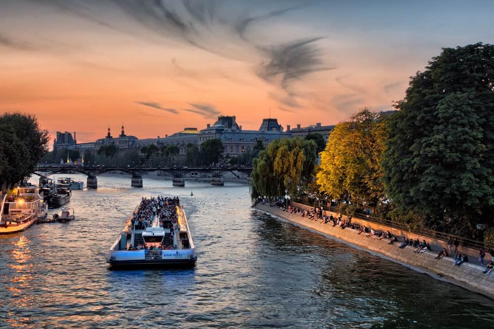Ein Boot unternimmt bei Sonnenuntergang Ausflüge den Fluss hinunter in Paris.